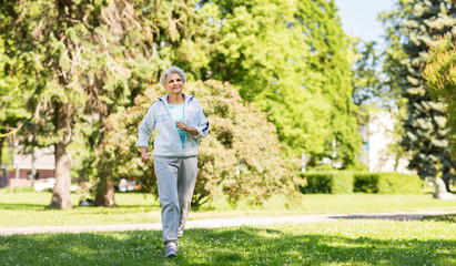fitness, sport and healthy lifestyle concept - senior woman running along summer park