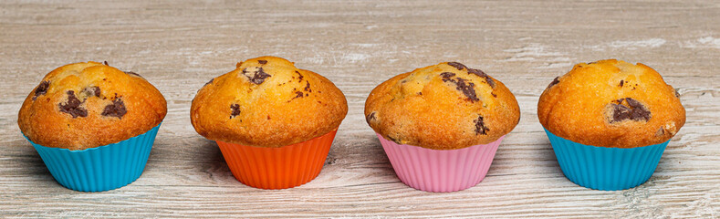 Muffinki w kolorowych foremkach. Słodkie babeczki na drewnianym blacie.