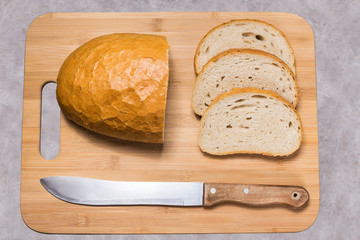 Chleb na desce do krojenia. Pół bochenka chleba i trzy kromki. Przygotowywanie kanapek. - obrazy, fototapety, plakaty