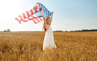 patriotism, independence day and country concept - happy smiling young girl holding national american flag waving over cereal field