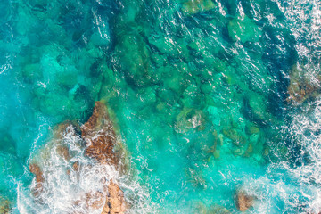 Rocky sandy beach with beautiful emerald water of Mediterranean Sea. Background top view