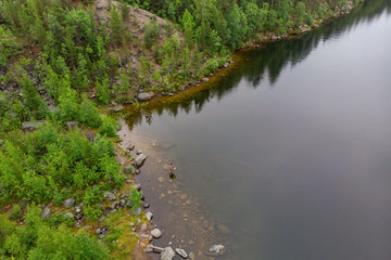 Fisherman man casts rod in mountain river in boots fly fishing salmon, morning. Aerial top view