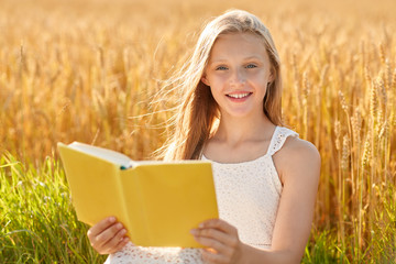 country, literature and leisure concept - smiling young girl in white dress reading book on cereal...