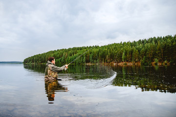 Fototapeta na wymiar Fisherman using rod fly fishing in mountain river summer splashing water