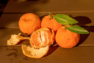 Freshly picked мandarin orange or tangerine on wooden table. Peeled mandarin