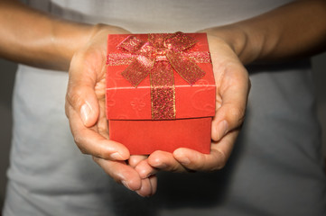 Female holding red present box in hand.