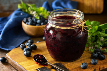 Organic Homemade Preserves. Blueberry jam in a jar and fresh blueberries on rustic wooden table....