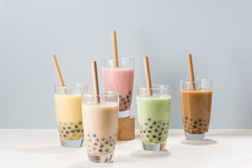 Five glasses of healthy milky boba or bubble tea flavored with fresh fruit and chocolate and served...
