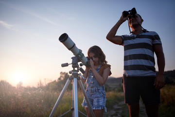 Father and daughter observing the sky with a telescope.