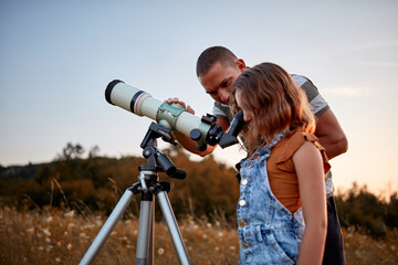 Father and daughter observing the sky with a telescope. © astrosystem
