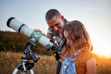 Father and daughter observing the sky with a telescope. © astrosystem