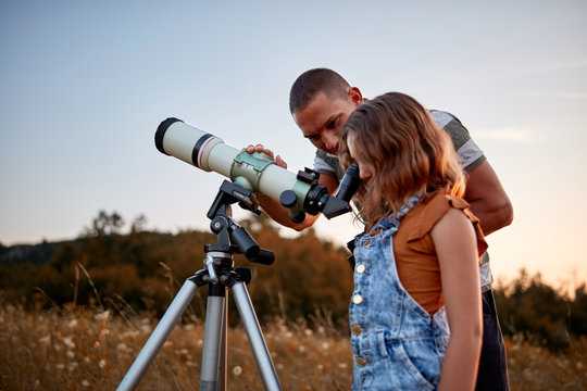 Father and daughter observing the sky with a telescope.