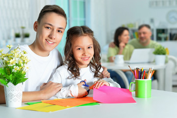 Fototapeta premium Portrait of brother and sister sitting at table and spending time together