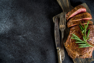 Cooked ready meat, Grilled beef steak with rosemary, on cutting board