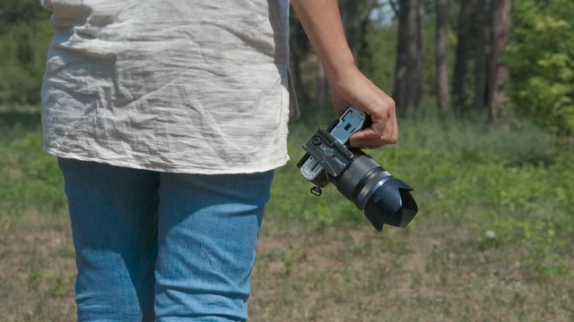 The girl walks with a camera in her hands.