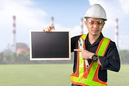 The abstract image of the engineer hold a empty board overlay with factory image. The concept of engineering, construction, city life and future.