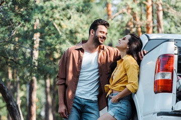 happy bearded man standing and looking at girl smiling near car