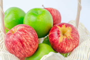 close up of mixed green and red apples in basket on white background.