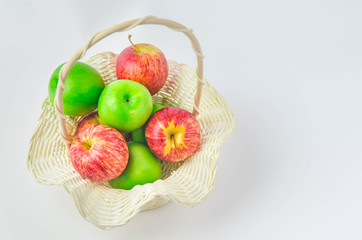 close up of mixed green and red apples in basket on white background.