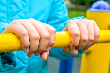 Child hands holding metal bar of children sports equipment on playground - 285263521