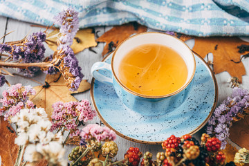 autumn warming tea on a wooden table with autumn tree leaves lying nearby