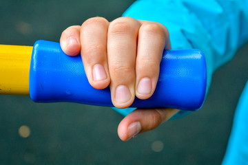 Child hand holding handle of children sports equipment on playground