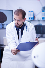 Fototapeta premium Close up portrait of brain surgeon looking into his notes from clipoard