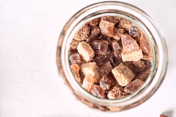 Brown cane sugar lump in a sugar bowl, top view. Concept diet, junk food, health.
