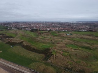 Obraz premium aerial view of hilly golf course with a city background