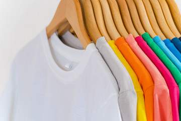 Obraz premium Close up of Colorful t-shirts on hangers, apparel background