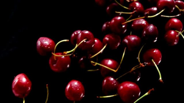 Rpe cherries fly on a black background closeup in slow motion
