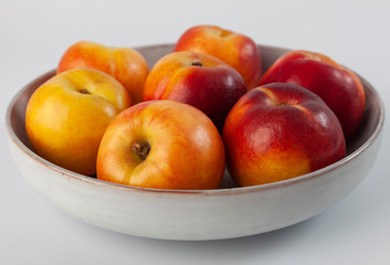 Juicy peaches are in a beige plate.