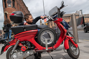 Fototapeta na wymiar Boy admiring a beautiful red motorbike