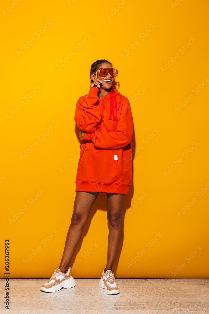 Sticker Image of cheerful african american woman wearing sunglasses and hoodie smiling at camera