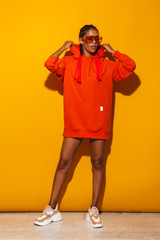 Image of confident african american woman wearing sunglasses and hoodie posing at camera