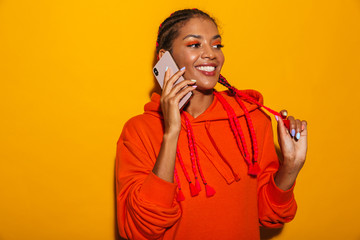 Image closeup of cheerful african american woman wearing hoodie shirt smiling while talking on cellphone