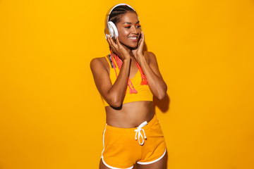 Image of attractive african american woman wearing afro braids smiling and listening to music with...