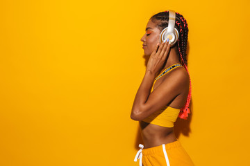 Image of pretty african american woman wearing afro braids listening to music with headphones