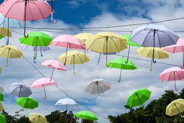 Fototapeta na wymiar colorful umbrella line wire moving by wind on blue sky white cloud