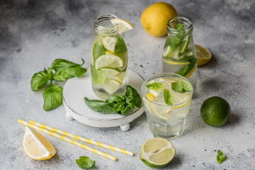 Summer basil lemonade on grey background. Fresh summer cocktail with basil, lemon and ice cubes. Homemade fresh lemonade with lemon and basil. Food and drink concept