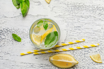 Summer basil lemonade on grey background. Fresh summer cocktail with basil, lemon and ice cubes....