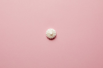 Top view of small white meringue in center on pink background