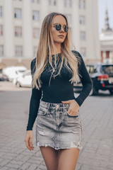 Beautiful young woman posing in the street, wearing sunglasses. Fashion summer photo.