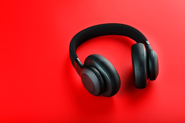 Obraz na płótnie Canvas Wireless black headphones on a red background. View from above. In-ear headphones for playing games and listening to music tracks