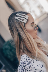 Close up portrait of a young blonde woman with natural hairstyle. Her tresses are adorned with...