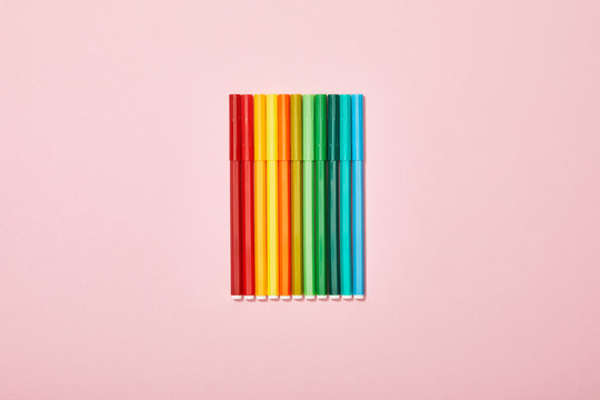 Top view of multicolored felt pens isolated on pink