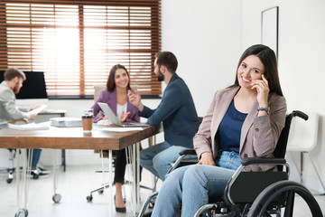 Young woman in wheelchair with colleagues at office