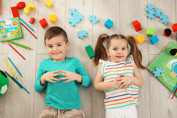Fototapeta premium Little children with toys and books lying on floor indoors, top view. Playtime