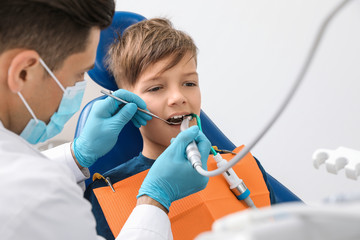 Professional dentist working with little boy in clinic