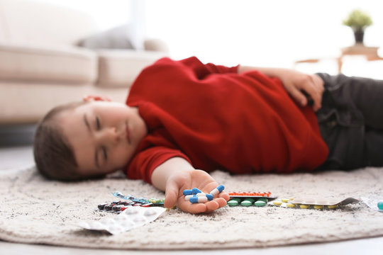 Unconscious Little Child With Pills Lying On Floor At Home. Household Danger